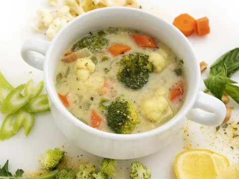 Bowl of vegetable soup with lemon and celery garnishes
