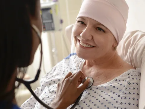 An adult female cancer patient receives treatment from a nurse.