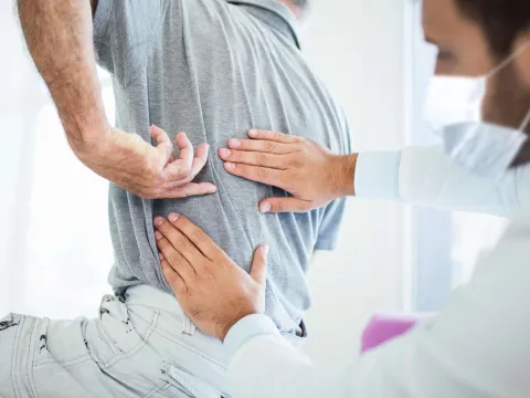 A man experiencing back pain at the doctor's office.