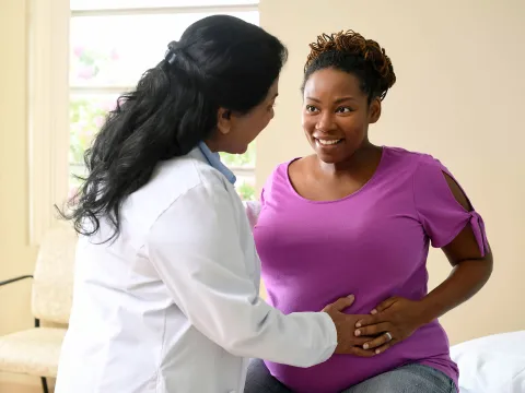 A nurse having a friendly conversation with a patient who is expecting a baby.