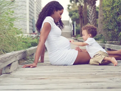 Pregnant Mother with son sitting outdoors.