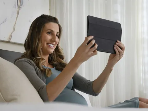 A pregnant woman watches a video on a tablet
