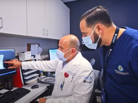 Dr. Michael Hawks (seated), orthopedic trauma surgeon and medical director for AdventHealth and Rothman Orthopaedics in Central Florida, confers with a fellow physician.