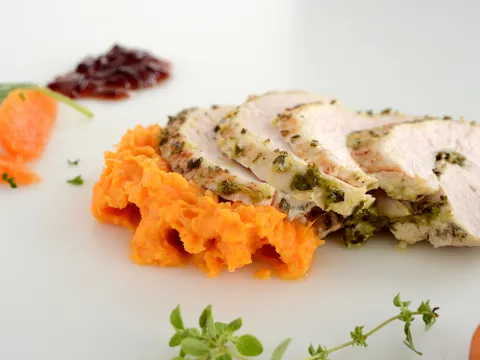 Four slices of turkey breast with sweet potato mash and garnishes