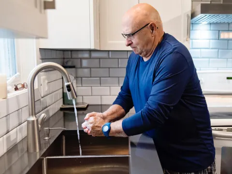 Senior man washing his hands at his home's kitchen sink