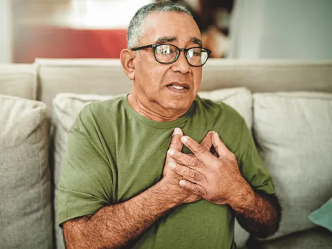 An older man holding his chest.