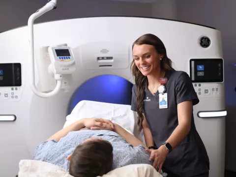 Female imaging technician preparing a male patient for a CT scan.