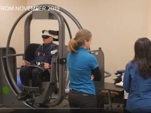 Man straps into vertigo chair as therapists monitor