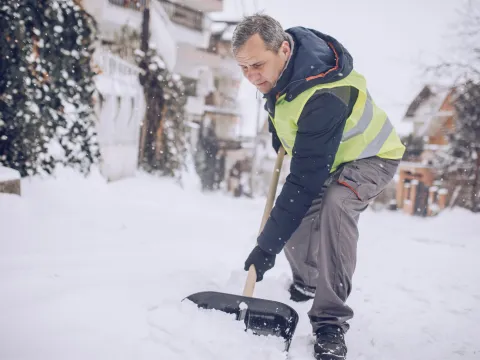 An older man shoveling snow.