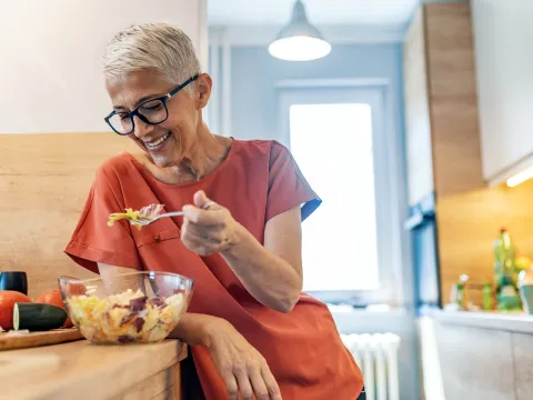 A woman eating a healthy salad at home.