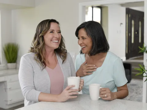 Two women laughing while having coffee together