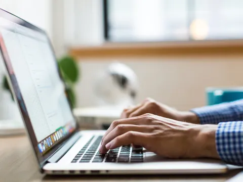 Fingers typing on a laptop