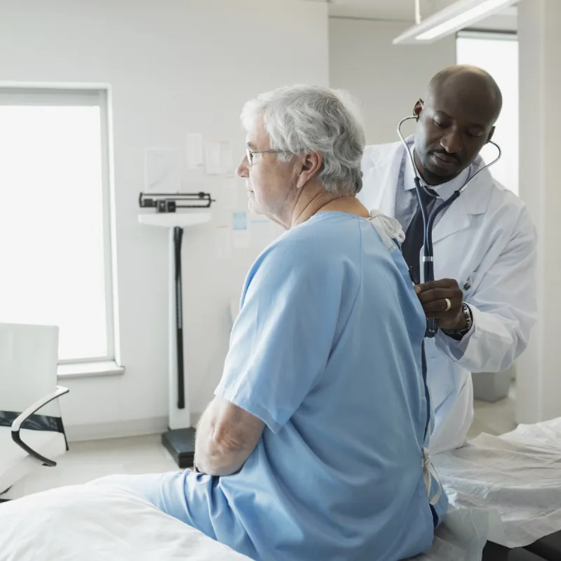 A Caucasian man receives a check-up an African American doctor.