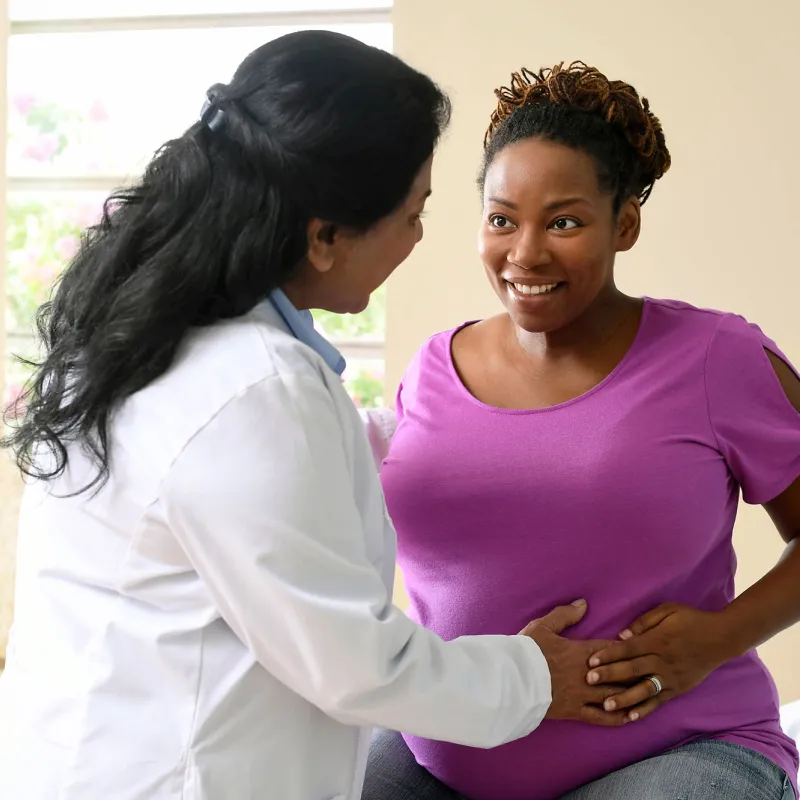 A nurse having a friendly conversation with a patient who is expecting a baby.
