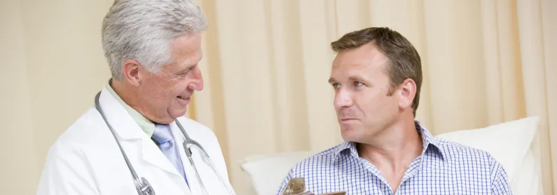 A doctor and his male patient (who is reclined) are consulting during an appointment.