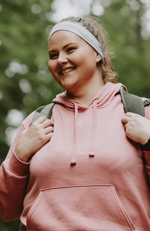 Woman smiling while she is on a hike outdoors.