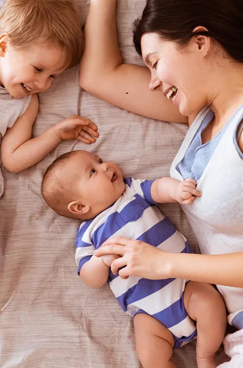 A mom snuggles her two children in bed.