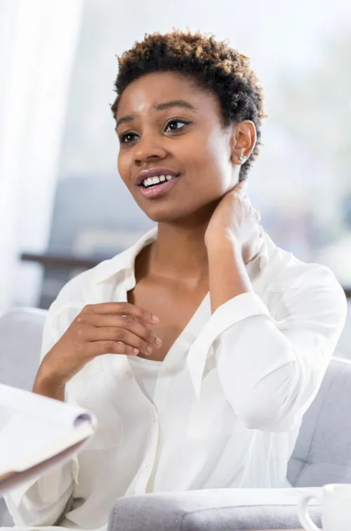 A young woman rubs her neck as she talks to a nurse