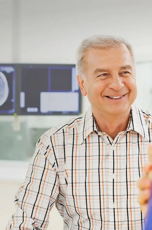 Man speaking with a doctor with imaging results on a screen behind him