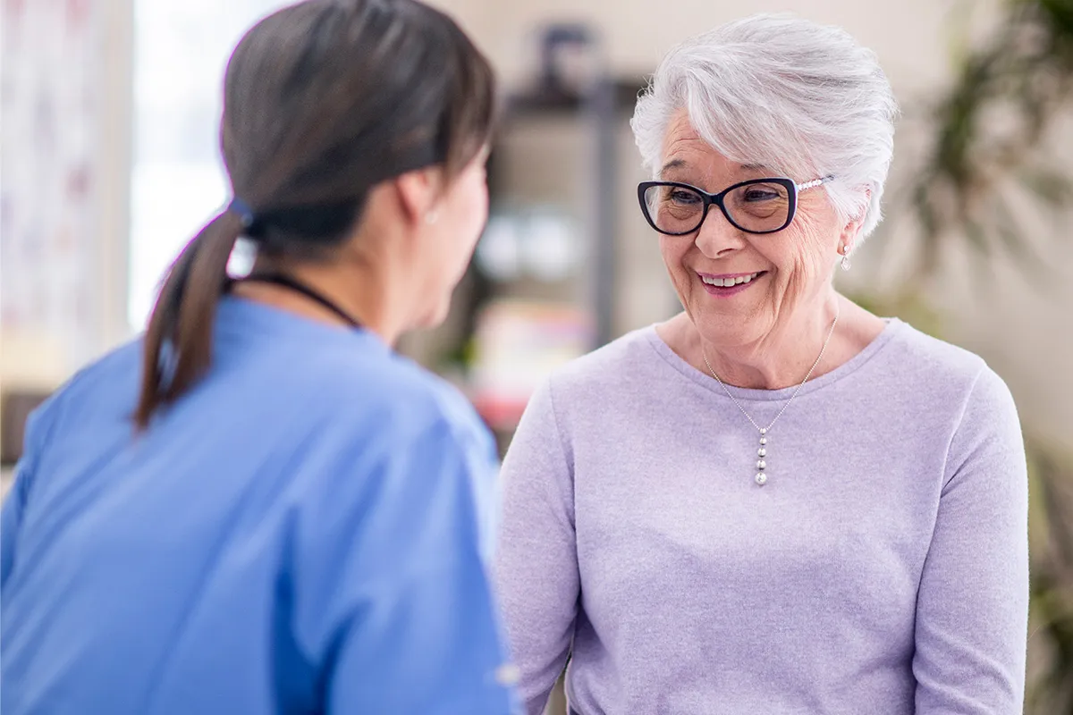 An elderly woman talking to a nurse.