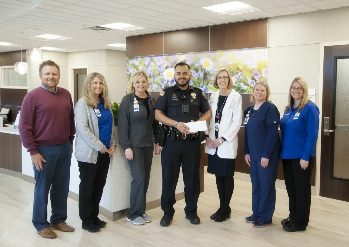 A group of people with a police officer holding an award.