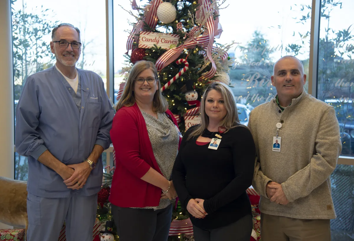 Group of people standing in front of a Christmas tree.